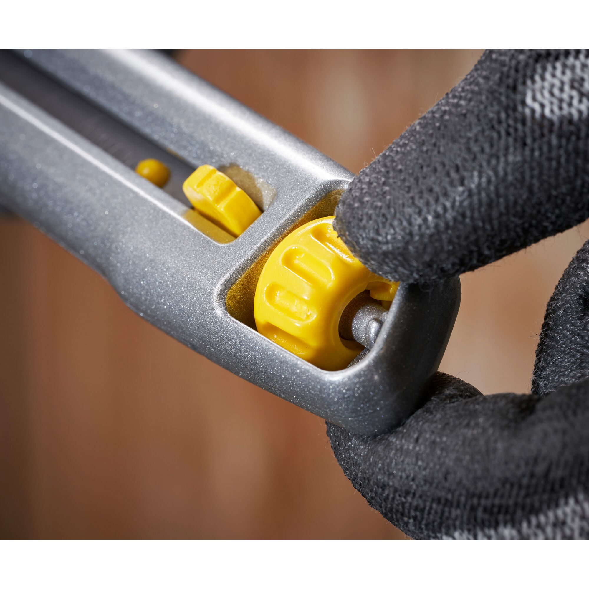 STANLEY 0-10-018 utility knife close-up, showing yellow adjustment wheel being turned with gloved hand.