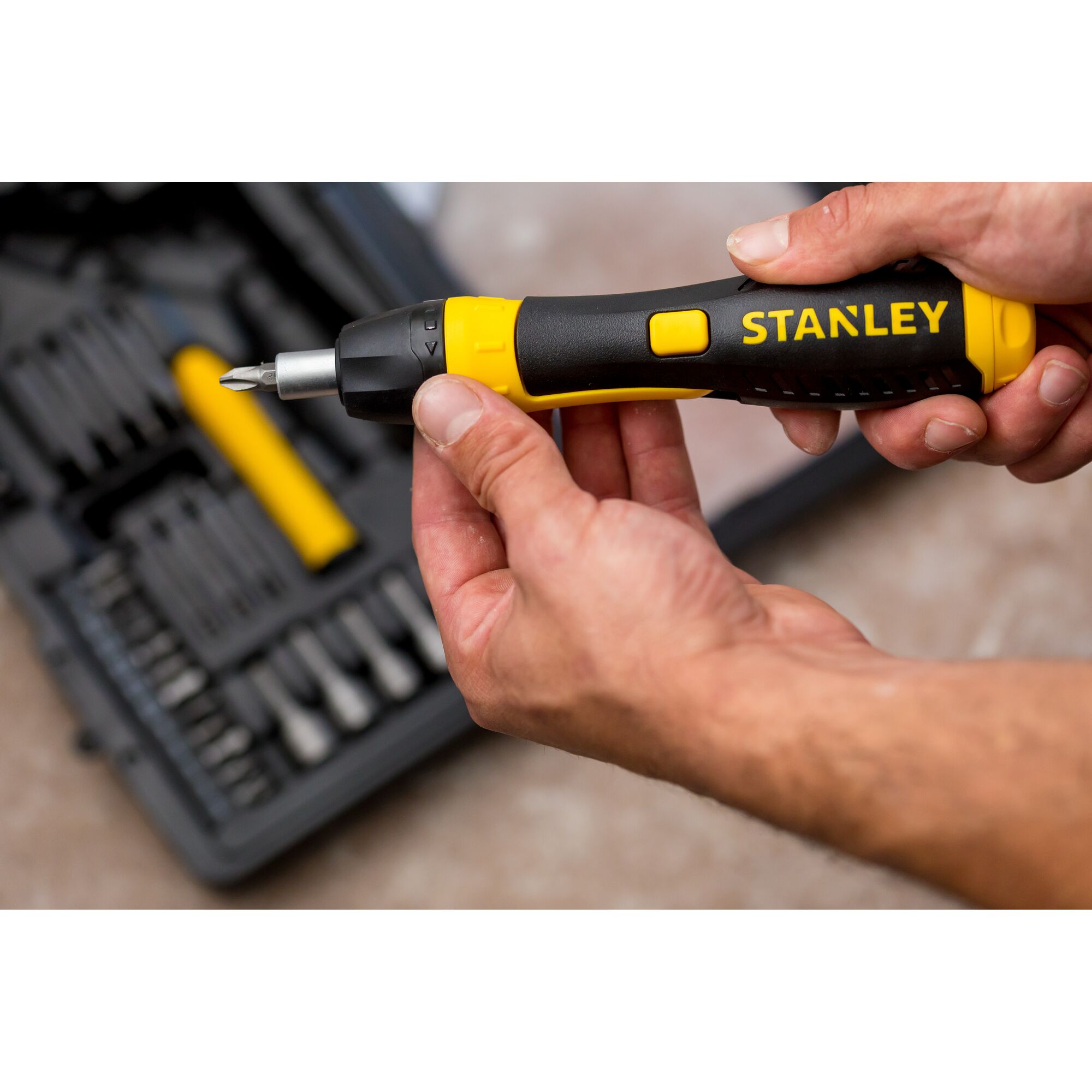 STANLEY 0-63-038 ratcheting screwdriver with black and yellow handle held in hand, tool kit in background.