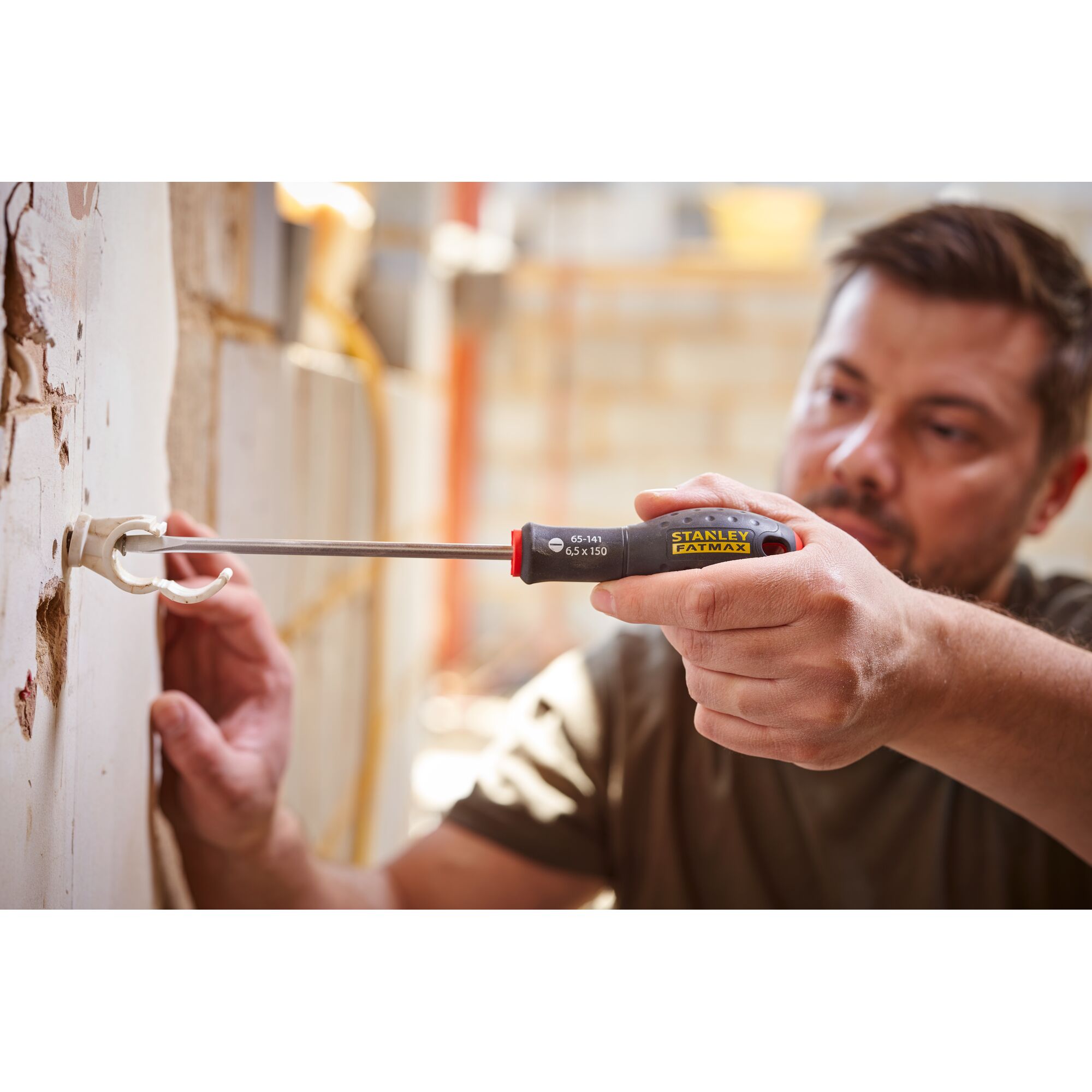 STANLEY 0-65-141 screwdriver with black and yellow handle used to install wall bracket, photo shows tool in use.