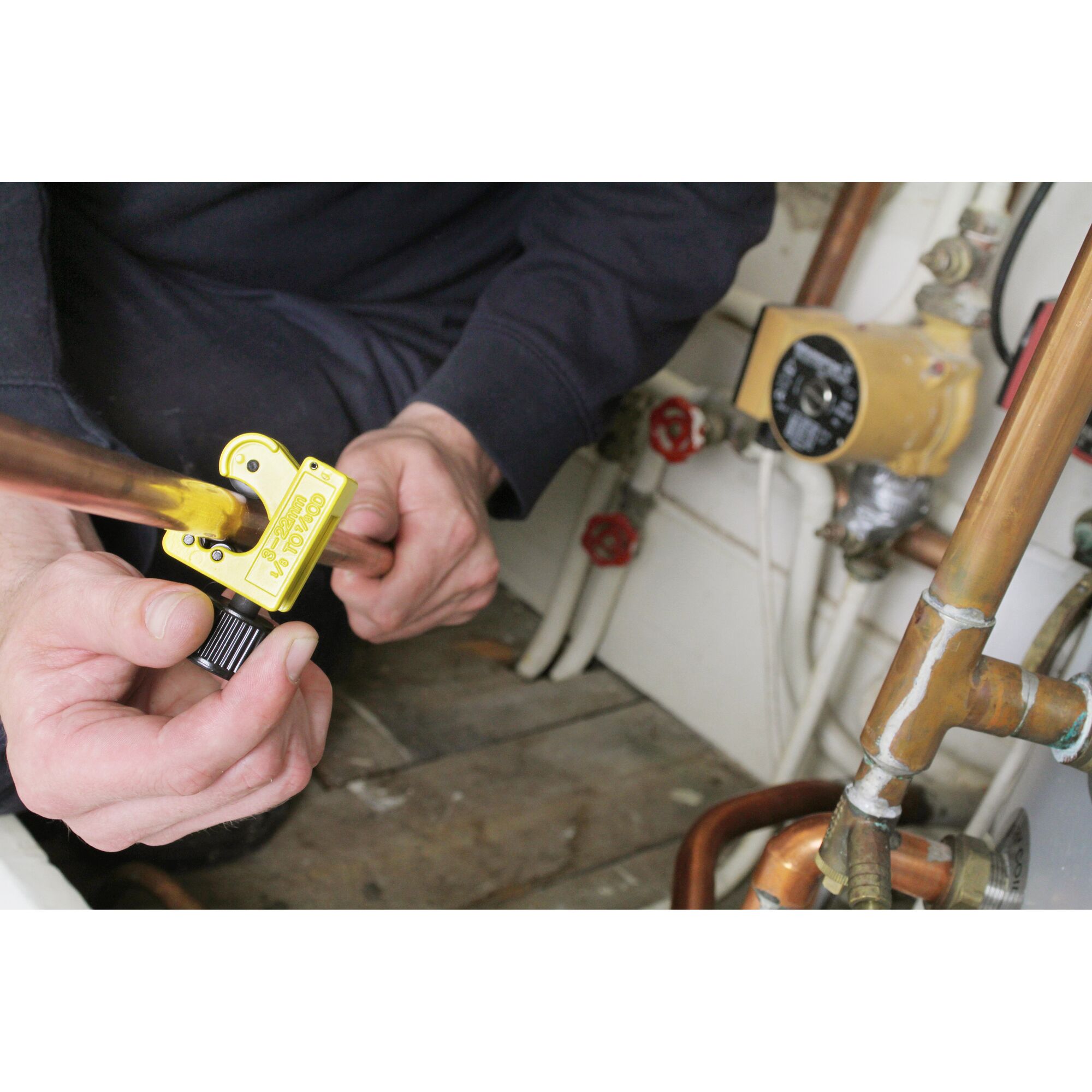 STANLEY 0-70-447 pipe cutter in use cutting copper pipe in plumbing setting.