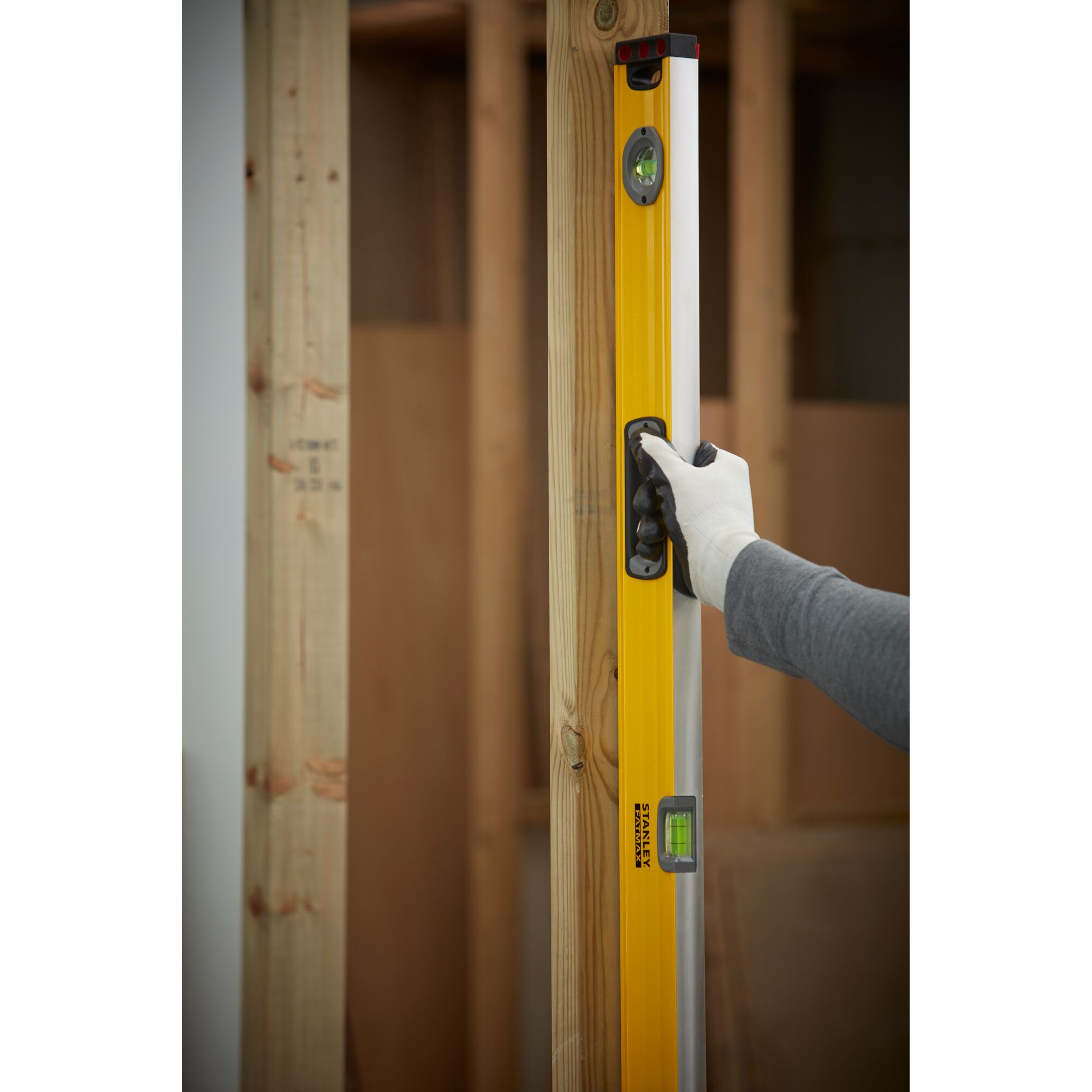 STANLEY 1-43-548 level tool held vertically against wooden frame, user wearing glove.
