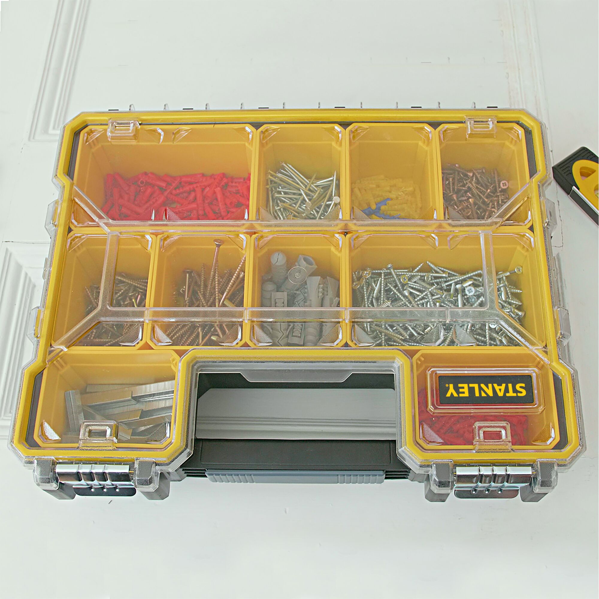 STANLEY 1-97-518 organizer box with transparent lid, yellow dividers, and assorted screws and anchors, top view.