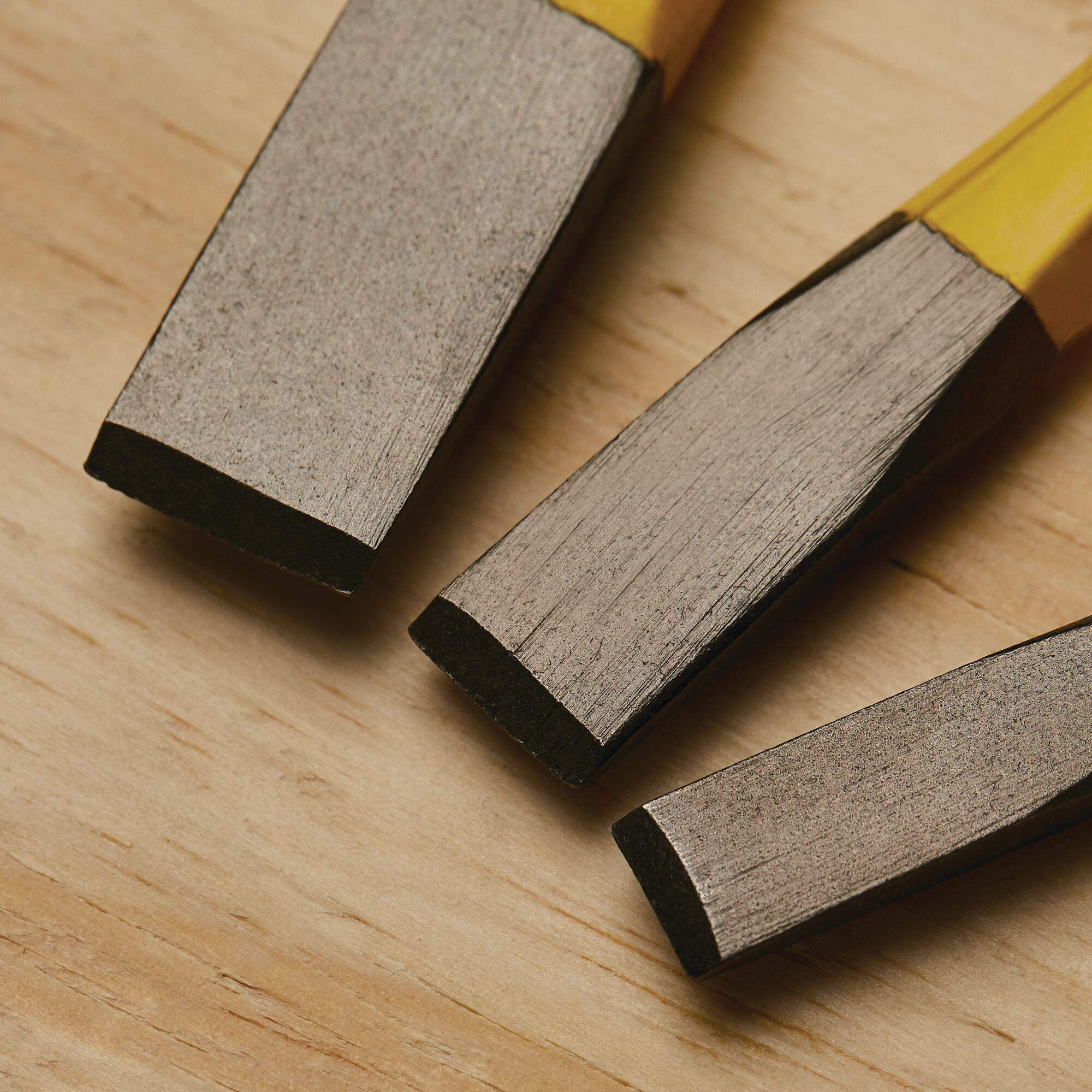 Stanley 16-299 chisel set close-up on wood surface, showing metal blades and yellow handles.