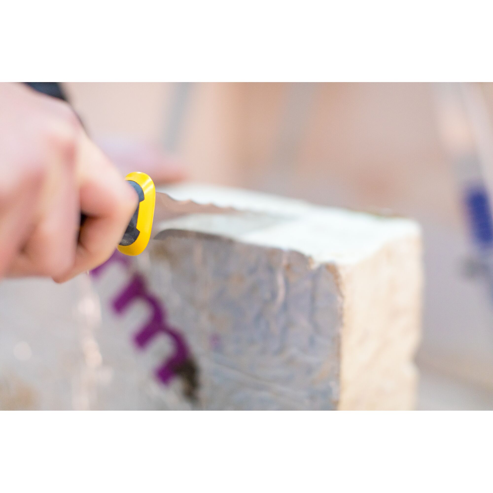 Photo of STANLEY FMHT0-10327 utility knife cutting insulation block, close-up view.