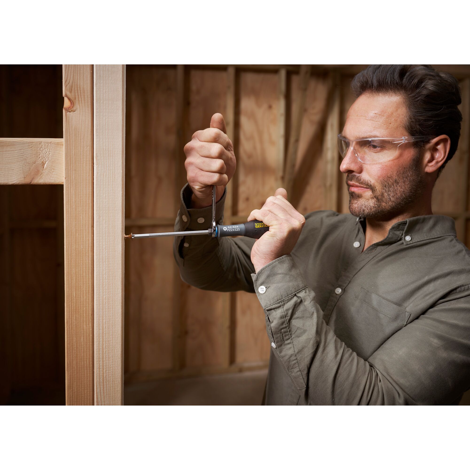 STANLEY FMHT0-62624 screwdriver in use by person attaching screw to wooden frame, close-up action shot.
