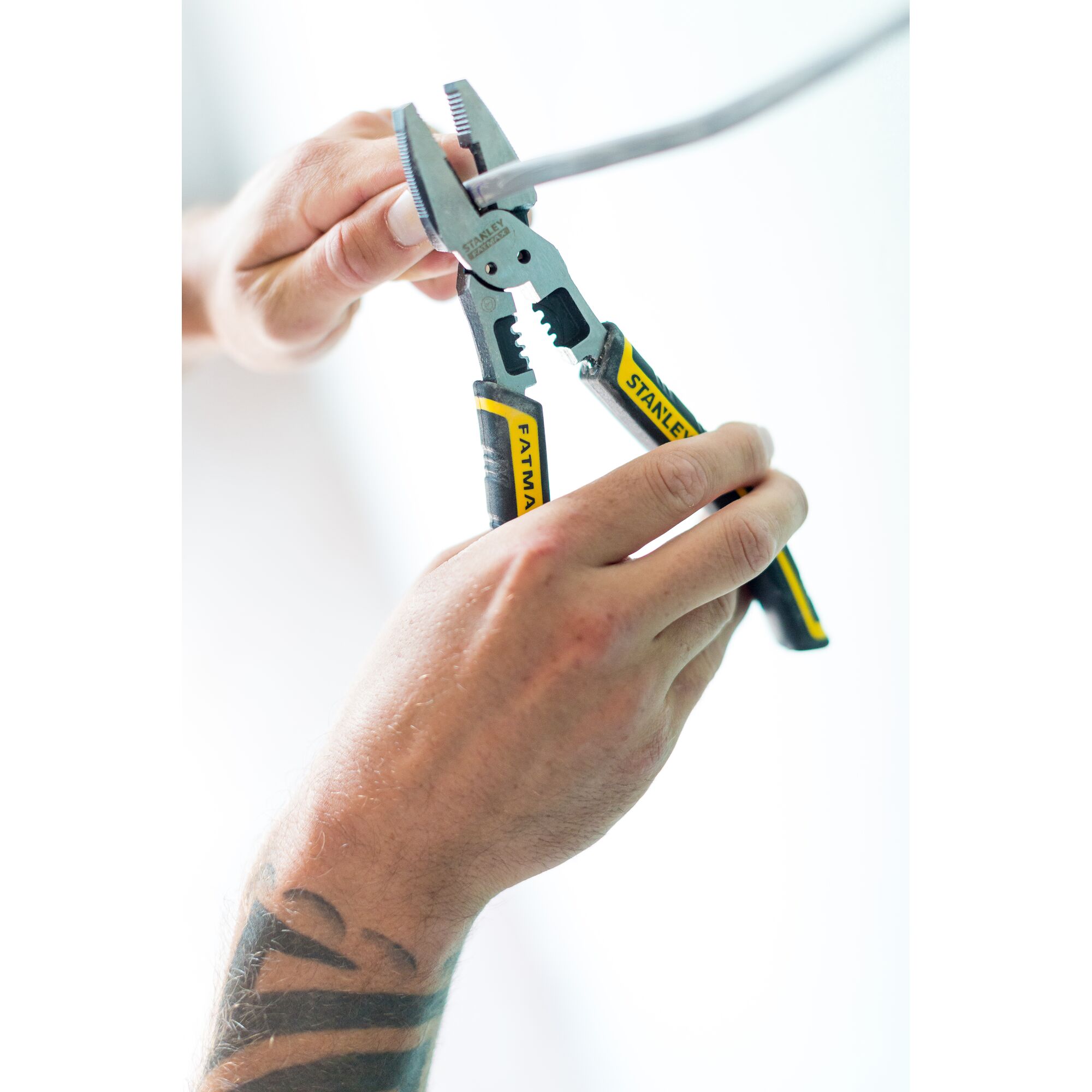 Photo of STANLEY FMHT0-75469 adjustable pliers with yellow and black handles in use, gripping a metal rod.