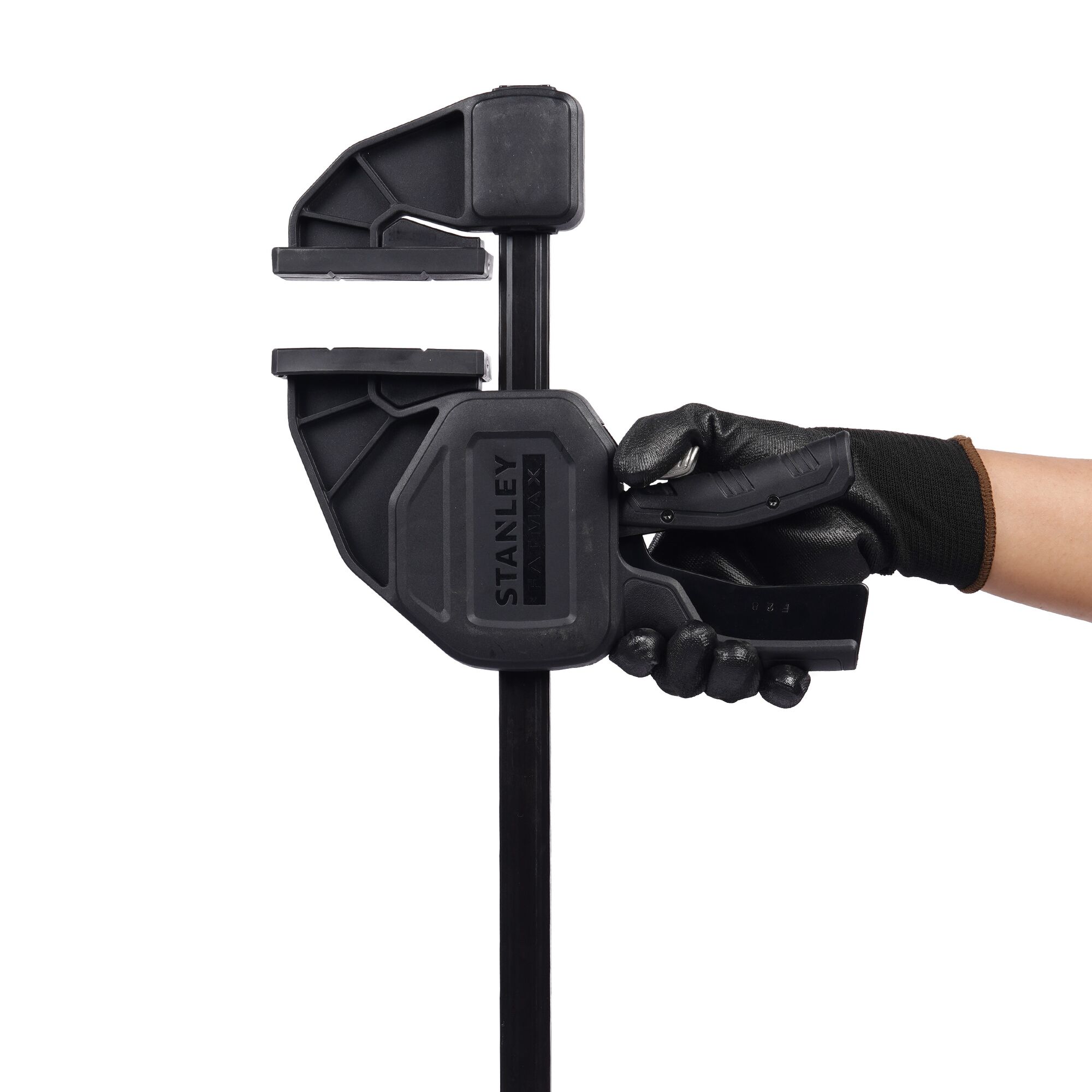 Stanley FMHT0-83240 bar clamp held by gloved hand, side angle, black plastic and metal construction.