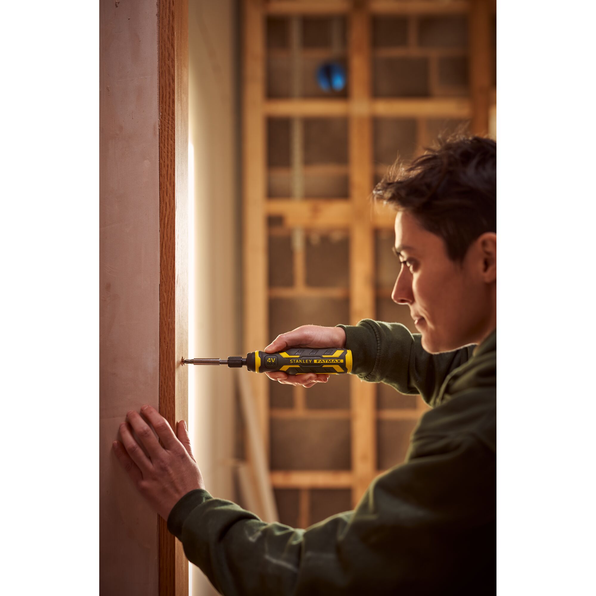 STANLEY FMHT66719-0 yellow cordless screwdriver held by person fixing screw in wooden frame.