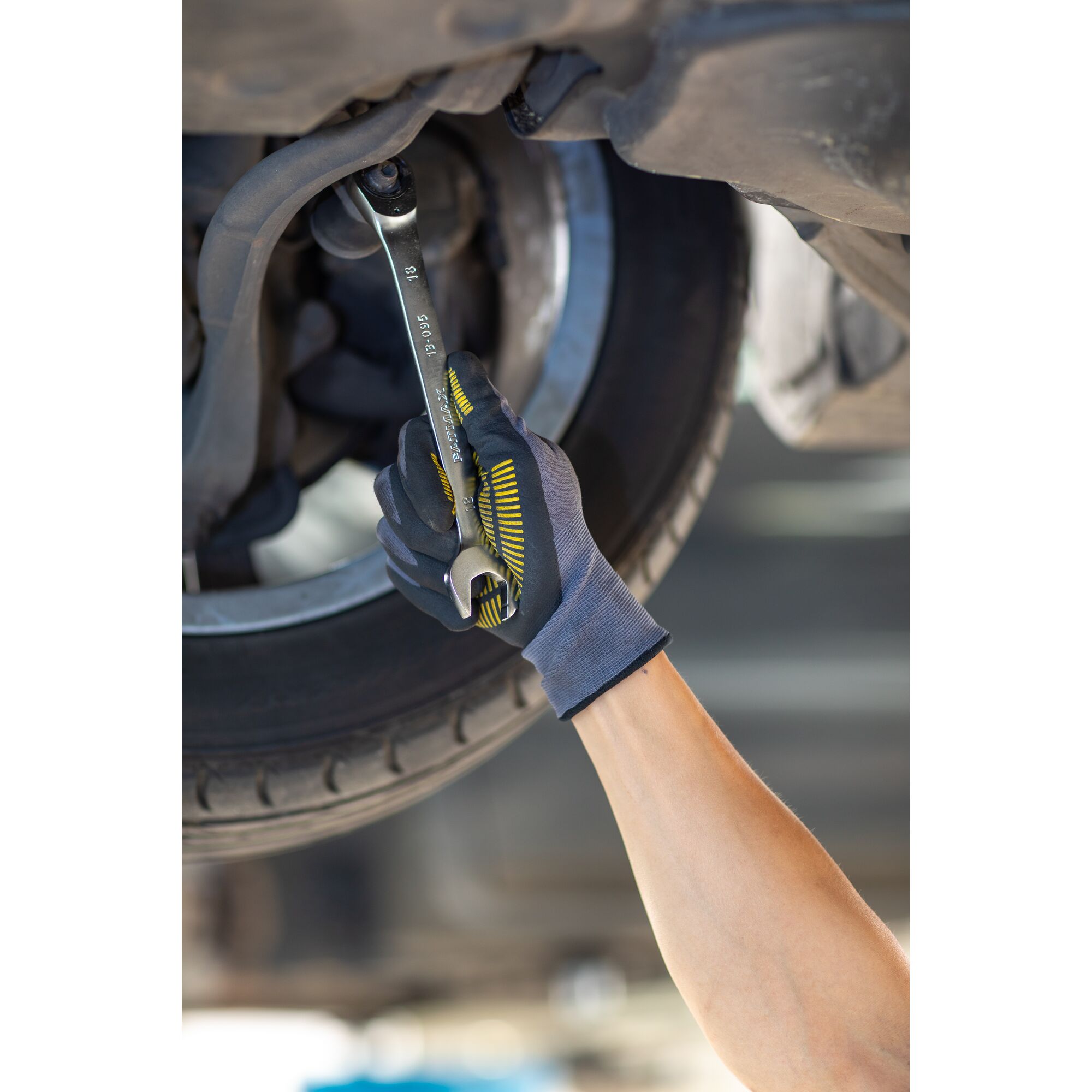 STANLEY FMMT13085-0 wrench used by gloved hand on car part, close-up photography.