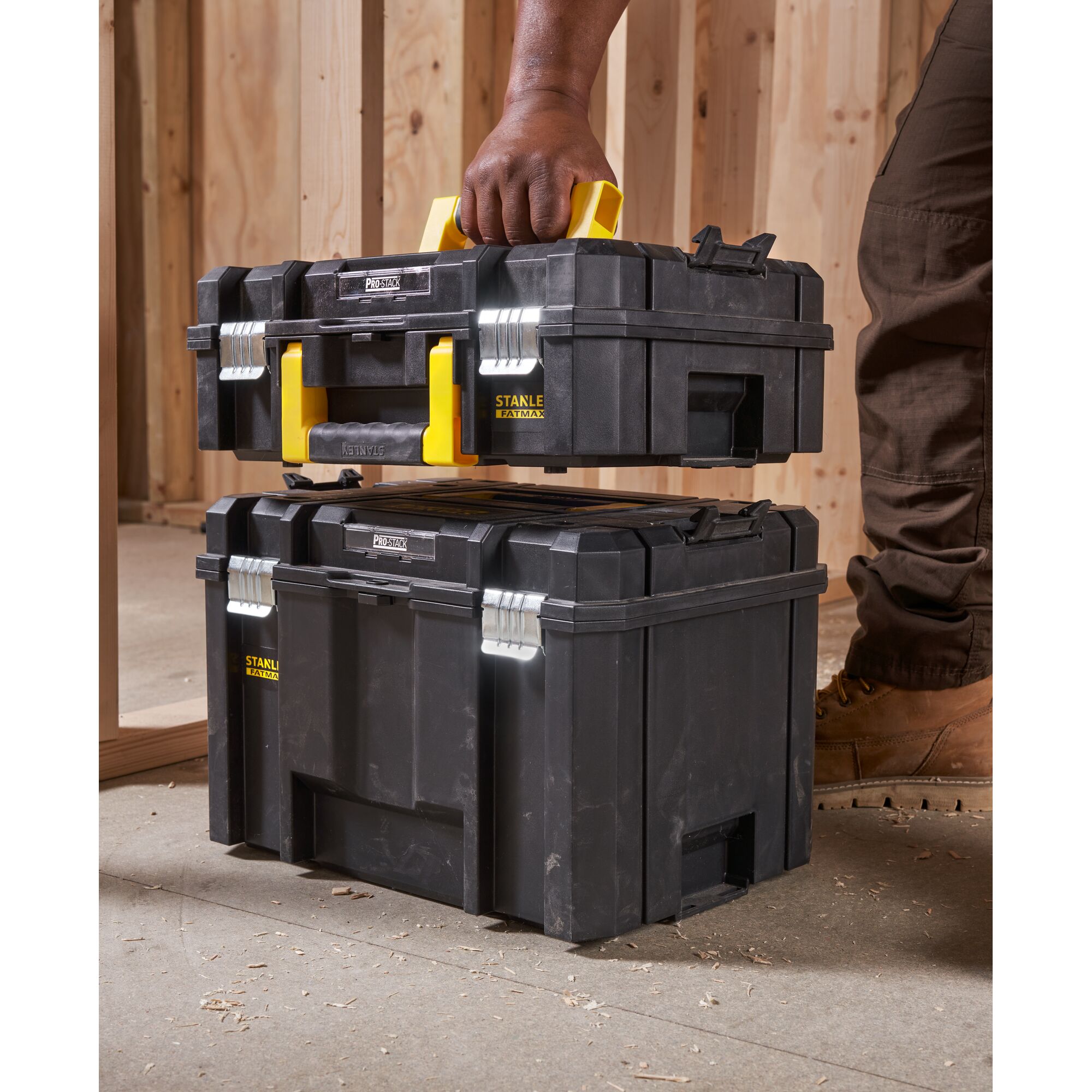 STANLEY FMST1-71966 black toolbox with yellow handle, side angle, stacked in construction site.