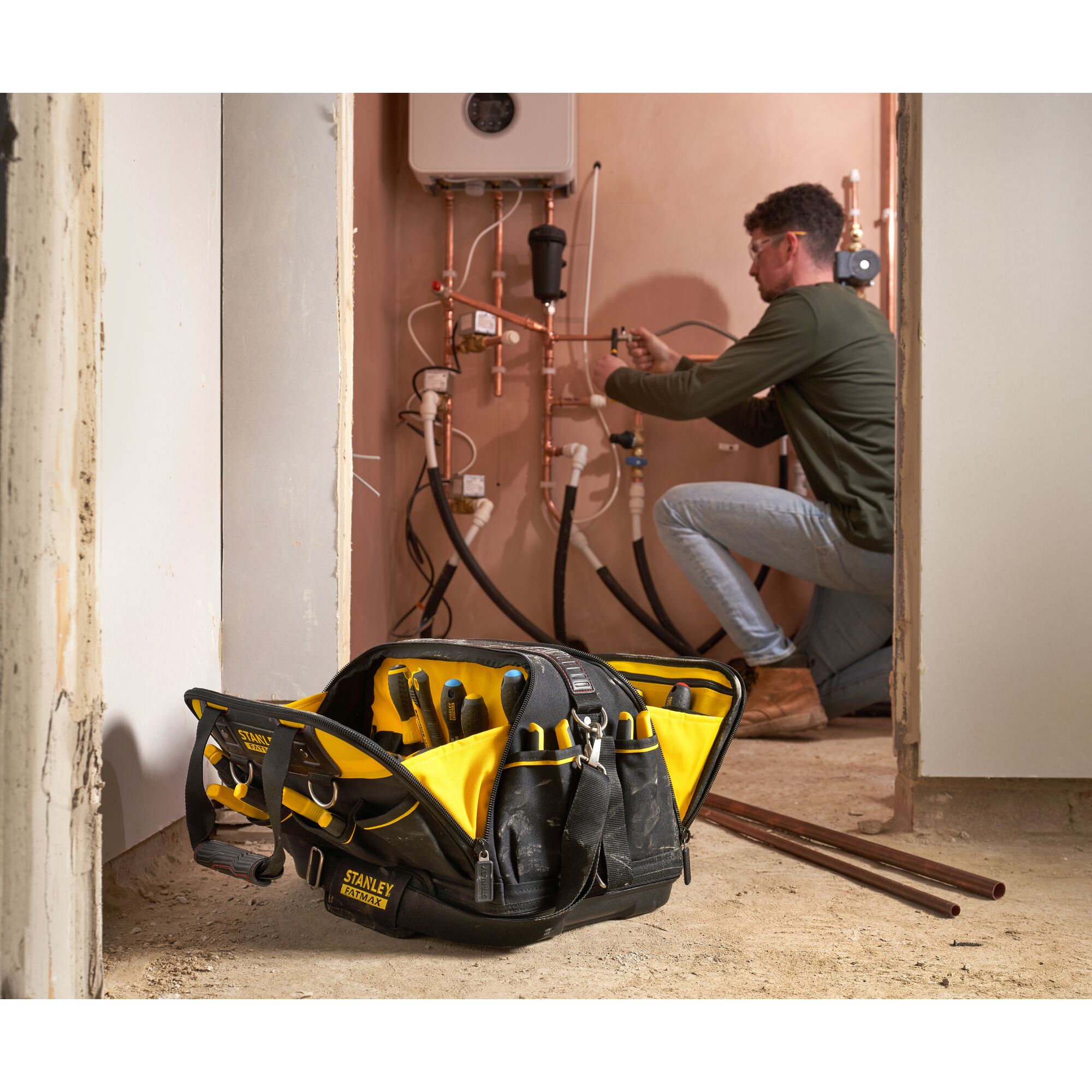 Photo of STANLEY FMST1-73607 tool bag with yellow and black compartments, filled with tools, in a worksite room.