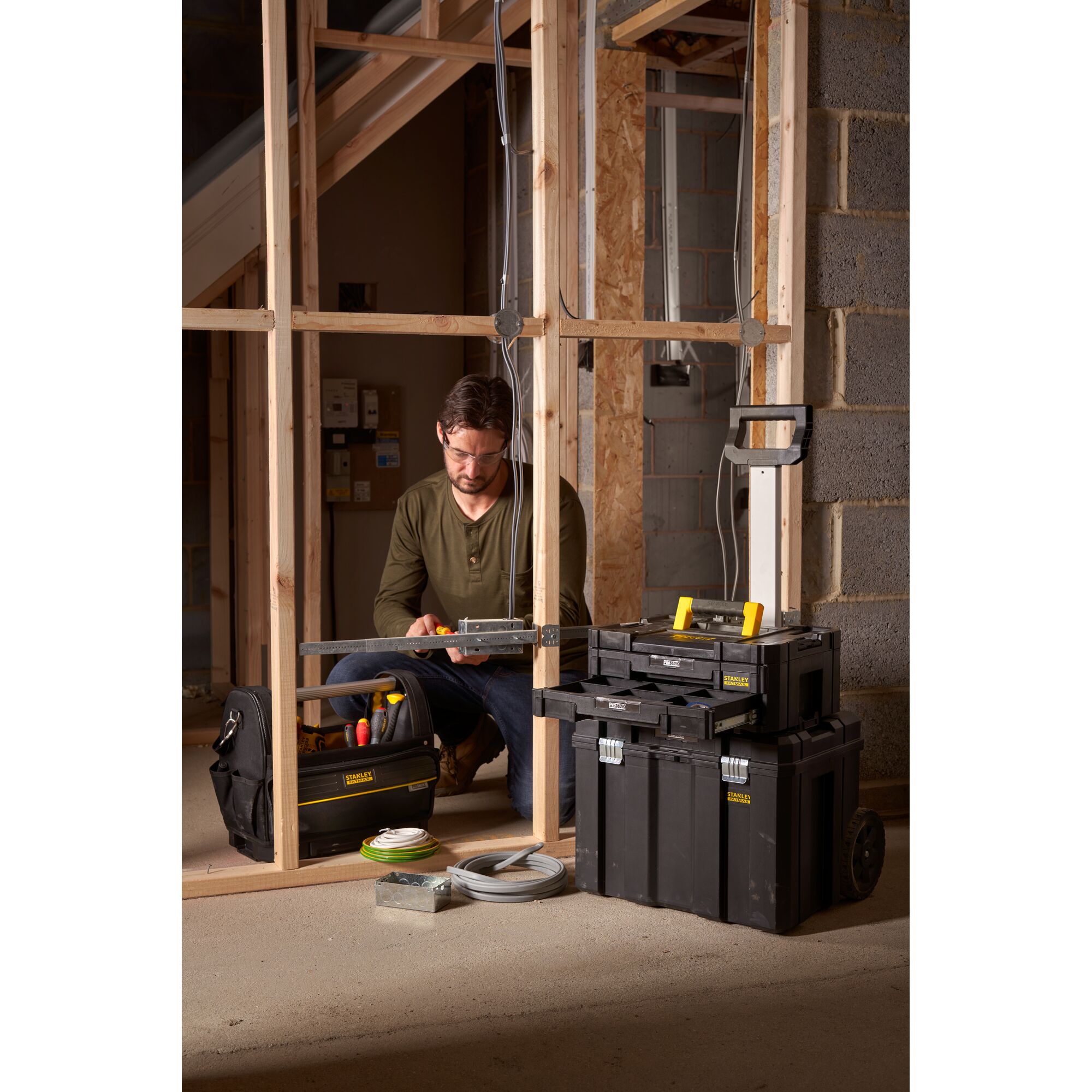 STANLEY FMST1-75753 black rolling tool box and organizer stack used at a construction site with a worker.