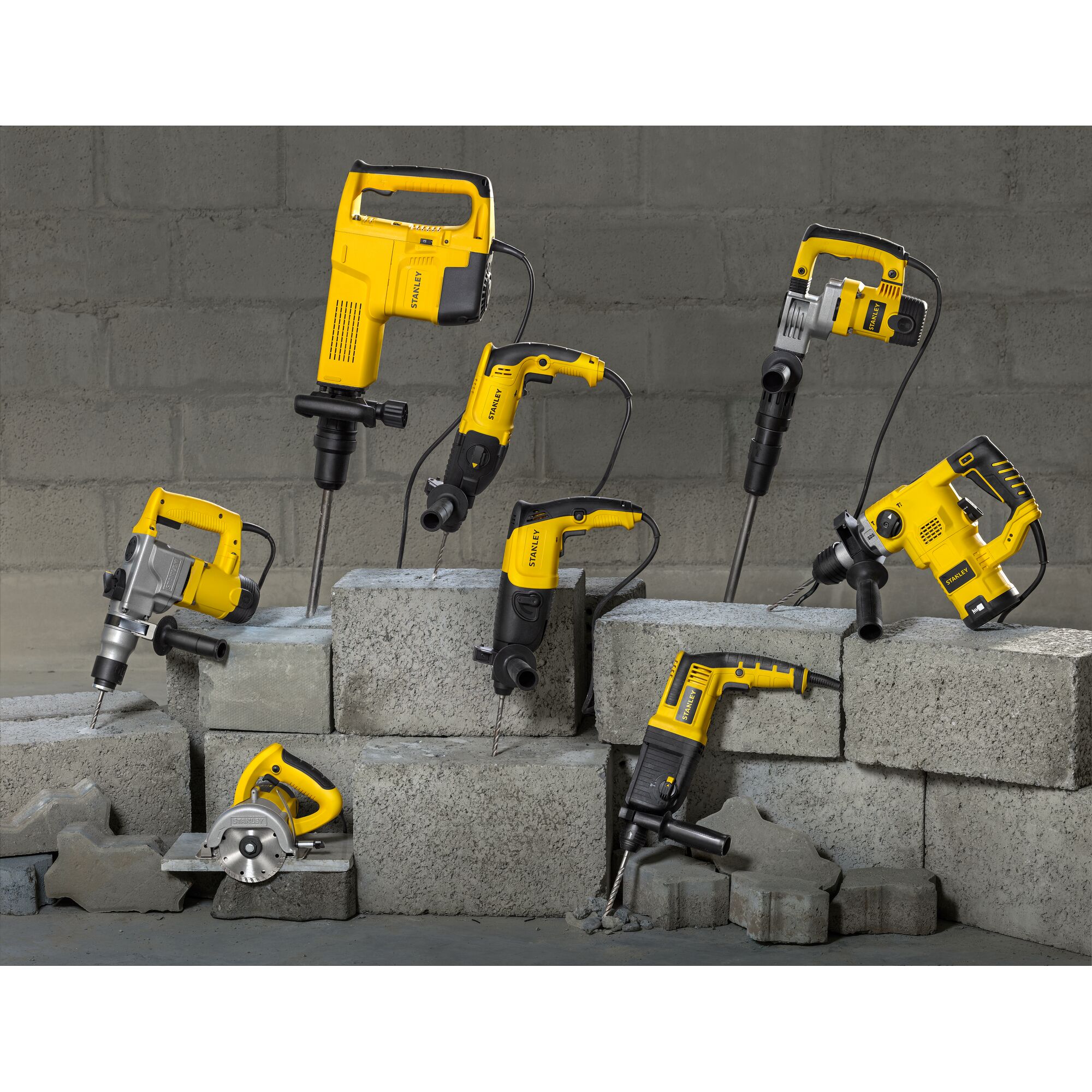 Photo of STANLEY SHR263K-BR power tools, including drills and saws, displayed on concrete blocks.