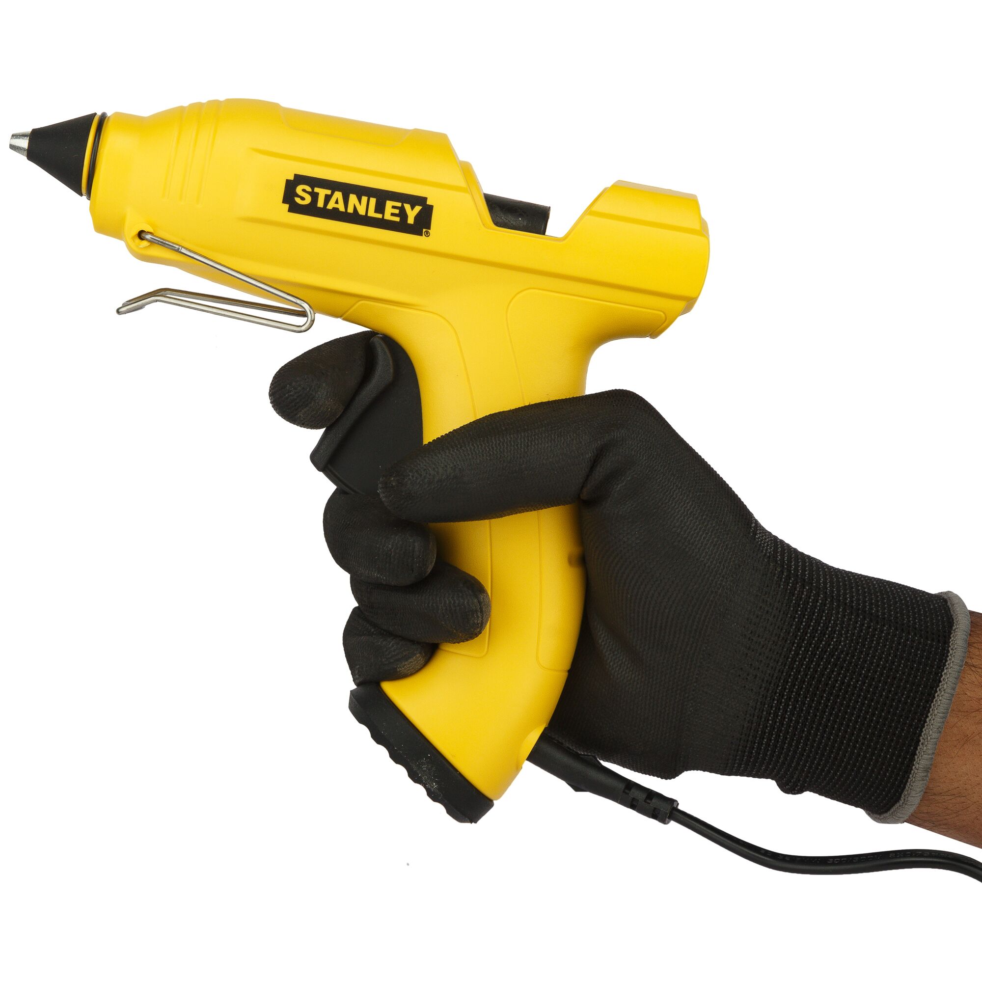 A gloved hand holding a yellow Stanley glue gun with a cord, used for craft and repair projects.