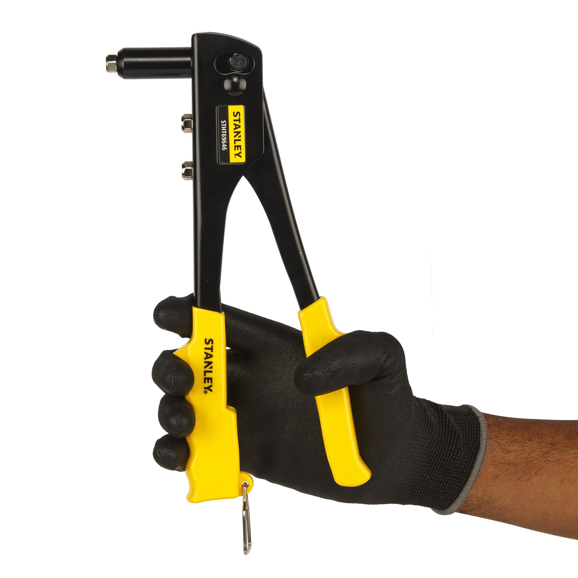 A hand in a black glove holds a Stanley STHT69646-8 rivet tool with yellow handles against a white background.