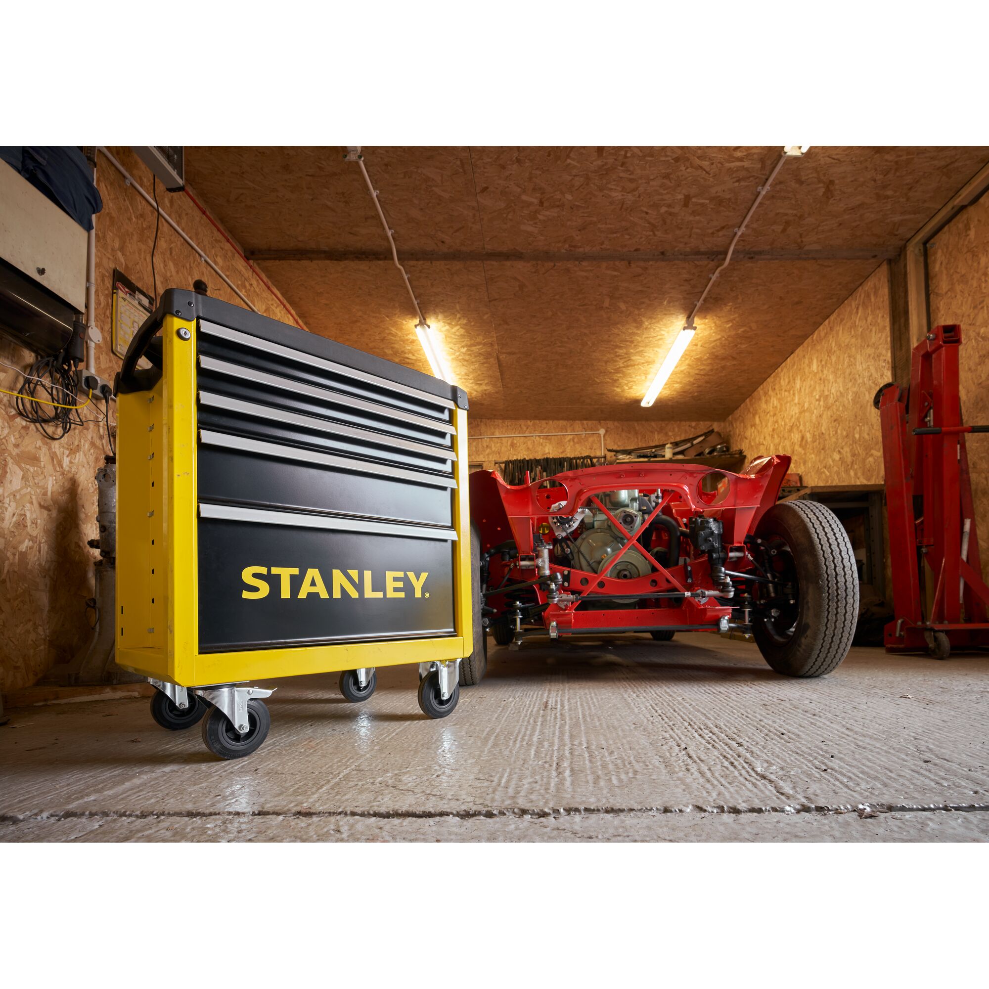 Photo of STANLEY STST74305-1 yellow and black rolling tool cabinet in a garage, shown front left angle.